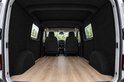 Binnenkant van een lege bestelwagen met zwarte viltwanden en een houten vloer, kijkend naar de voorstoelen.