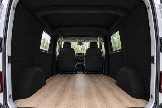 Binnenkant van een lege bestelwagen met zwarte viltwanden en een houten vloer, kijkend naar de voorstoelen.