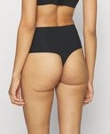 Zwarte high-waist string van gladde, naadloze stof, gezien van achteren op een model.
