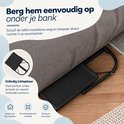 Zwarte laptoptafel in opgevouwen stand onder een bank geschoven voor ruimtebesparing.