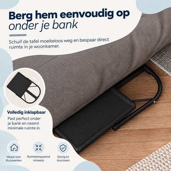 Zwarte laptoptafel in opgevouwen stand onder een bank geschoven voor ruimtebesparing.