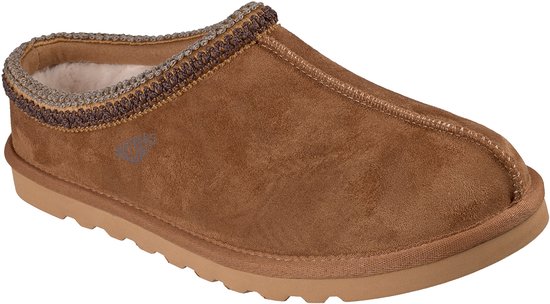 Bruine suède Skechers pantoffel met warme voering, gevlochten kraag en Skechers logo aan de zijkant.