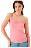 Model draagt een roze kanten top met spaghettibandjes en een spijkerbroek
