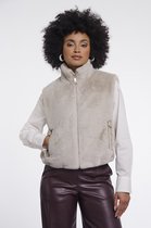 Crèmekleurig, kort, fluffy gilet met ritssluiting en opgestikte zakken. Gedragen door een model met krullend haar.