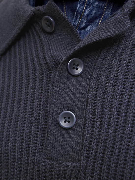 Sluiting van een donkerblauwe gebreide polo met knopen en een denim kraag.