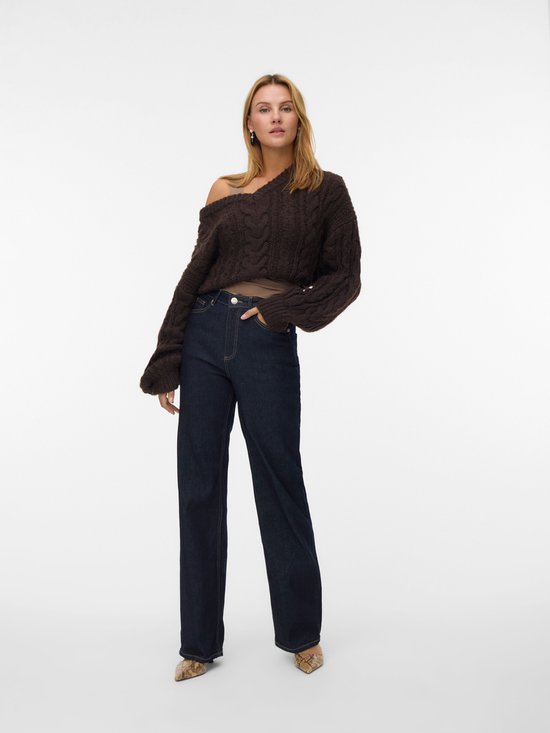 Model in donkerblauwe jeans met wijde pijpen, bruine kabeltrui en slangenprint pumps.