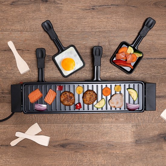 Zwarte raclette grill met zalm, hamburger, aardappel, ui en paprika. Twee pannetjes met ei en groenten.