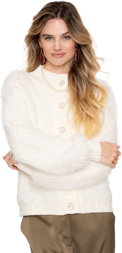Model draagt een off-white, harig vest met knopen, gecombineerd met bruine broek en parelketting.