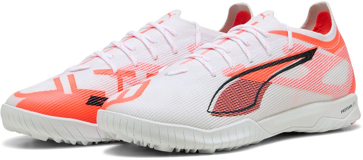 Puma Ultra 5 Pro Cage Low voetbalschoenen in wit met oranje details, lichtgewicht mesh bovenwerk en ondersteuningsframe.