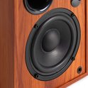Close-up van de woofer van een houten boekenplank speaker met een zwart membraan.