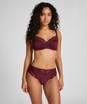 Vrouw in bordeauxrode bh met stipjes en kanten rand, en bijpassende broek met kanten details.