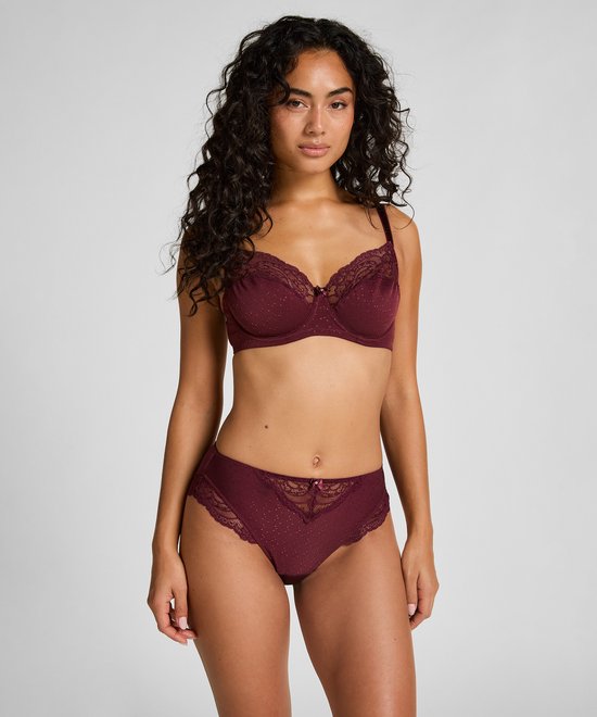 Vrouw in bordeauxrode bh met stipjes en kanten rand, en bijpassende broek met kanten details.