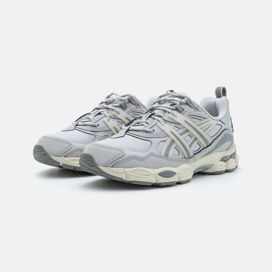 Grijze ASICS sneakers met beige accenten en veters. Gedetailleerde overlays.