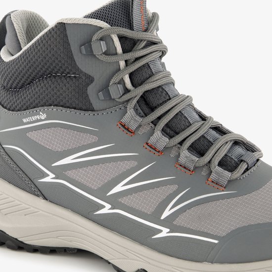 Detail van grijze wandelschoen met 'WATERPROOF'-tekst en witte strepen.