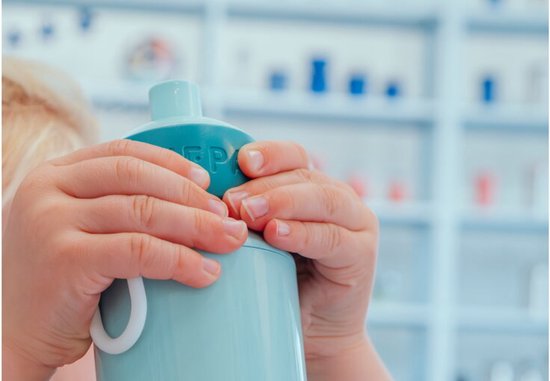 Mains d'enfant tenant une gourde Mepal bleu clair avec anse blanche.