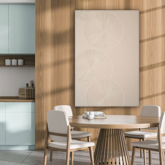 Beige canvas met drie cirkels in reliëf, hangend in een eetkamer met houten tafel en stoelen.