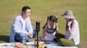 Een Insta360 camera op een selfiestick in het midden van een picknick met een familie.