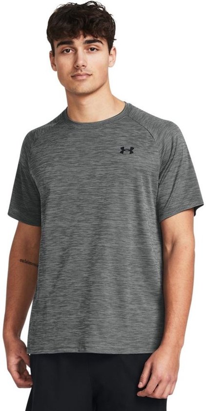 Man draagt grijs sportshirt met subtiel streepmotief en zwart Under Armour logo.