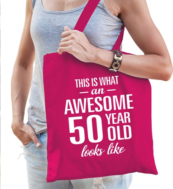 Fuchsia tas met witte tekst: 'THIS IS WHAT AN AWESOME 50 YEAR OLD looks like'. Gedragen door een vrouw.
