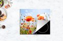 Een inductiebeschermer met een veld met klaprozen en korenbloemen op een aanrecht.