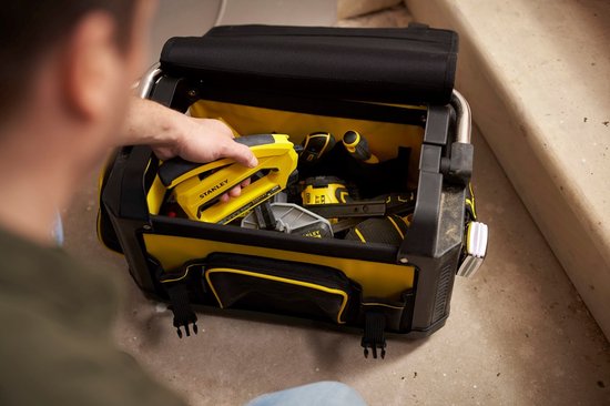Hand pakt een gele nietmachine uit een geopende zwarte en gele STANLEY FatMax gereedschapstas.