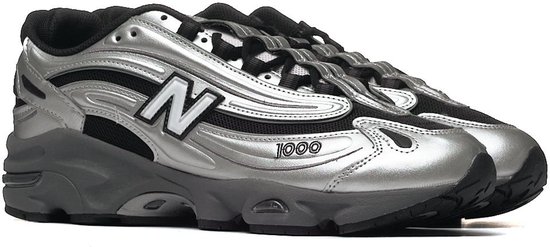 Paar zilverkleurige New Balance 1000 sneakers met zwarte details, op de voorgrond.
