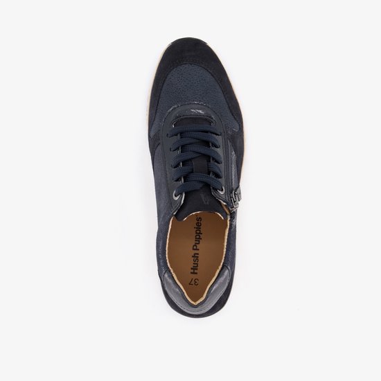 Bovenaanzicht van een donkerblauwe suède sneaker met 'Hush Puppies' logo op de binnenzool.