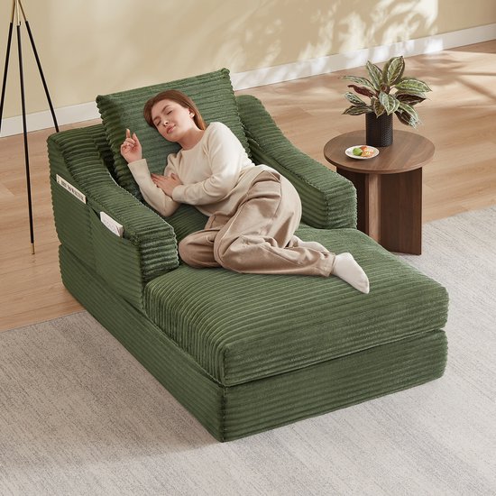 Groene corduroy fauteuil met een uitklapbaar bed, met een vrouw erop die slaapt.
