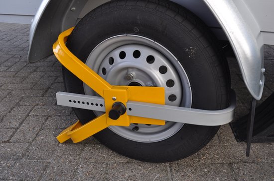 Gele wielklem die een autoband van een aanhanger beveiligt.