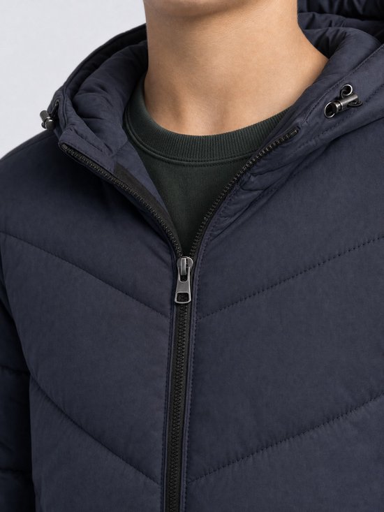 Detail van de kraag en rits van een donkerblauwe jongensjas met capuchon.