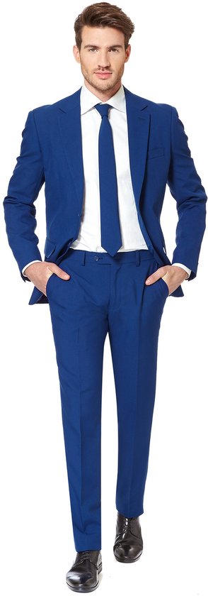 Man staand in een donkerblauw OppoSuits pak met handen in de zakken, wit overhemd en blauwe das.