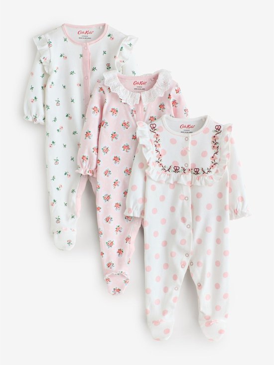 Set van drie babypyjama's: wit met roze stippen en geborduurde kraag, wit met bloemenprint en roze bies, en roze met bloemenprint en kanten kraag.