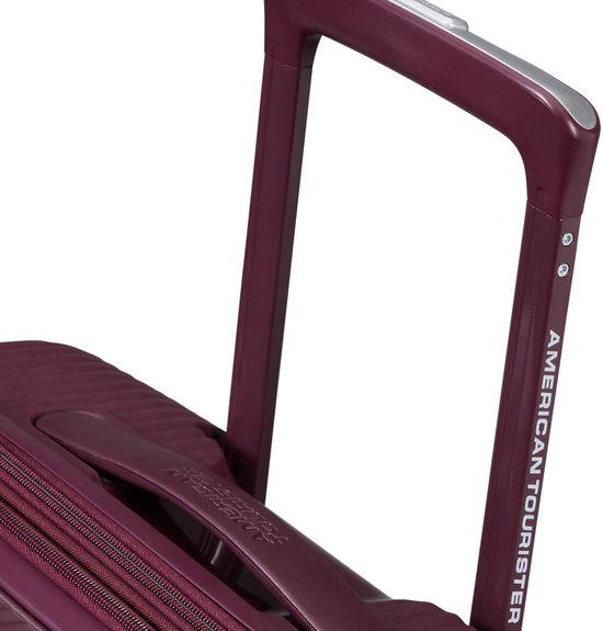 Uitschuifbare handgreep van een bordeauxrode American Tourister koffer met "AMERICAN TOURISTER" logo.