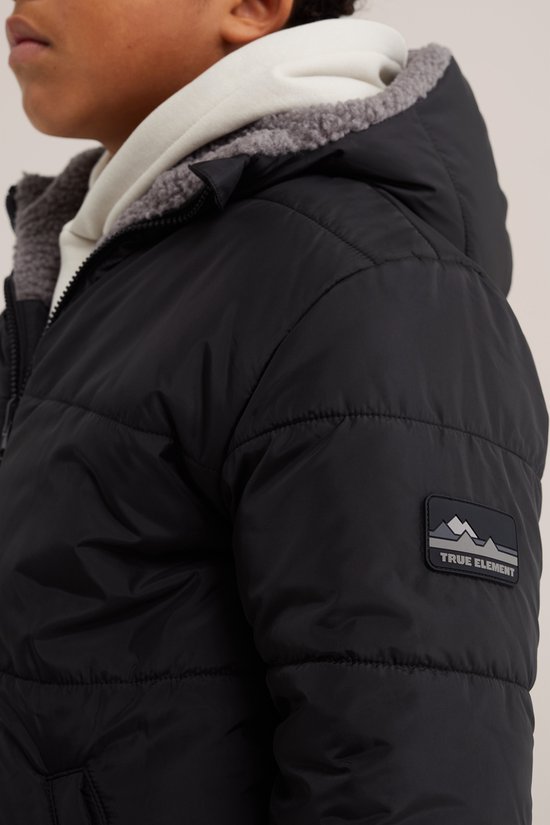 Jongen in zwarte jas met capuchon, beige hoodie eronder en een 'True Element' logo op de mouw.