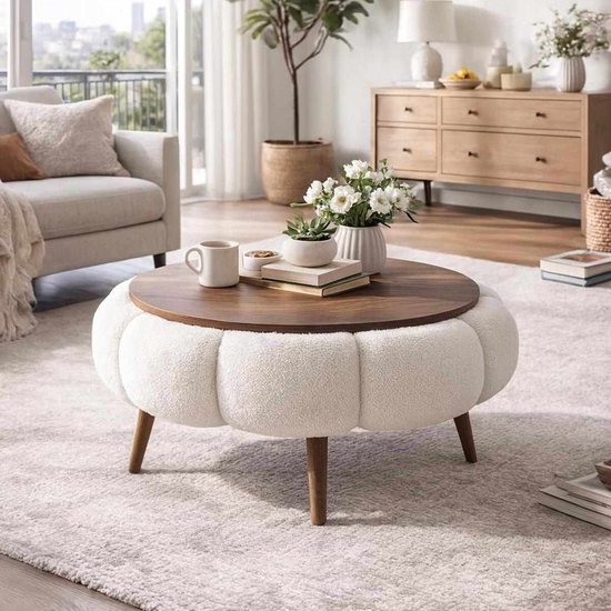 Ronde salontafel met witte, gepofte stoffen basis, houten blad en houten poten, in een woonkamer.
