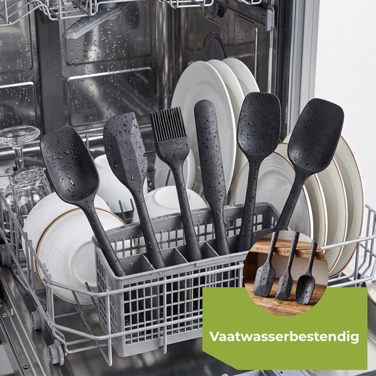 Zes zwarte siliconen spatels, nat van de vaatwasser, in een mandje tussen de witte borden.