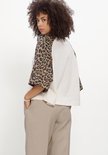 Wit raglan T-shirt met korte, wijde mouwen met luipaardprint. Gedragen door een model met een beige broek.