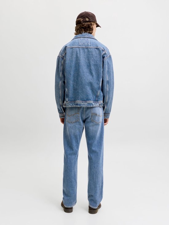 Achterkant van een man in een denim spijkerjasje en rechte jeans, met een bruine pet en schoenen.