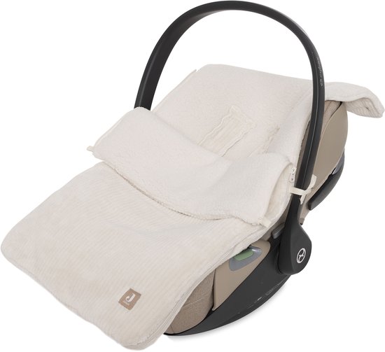 Wieg in een beige autostoel met een zachte, beige voetenzak van corduroy.