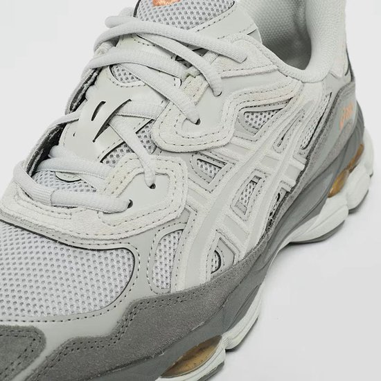 Detail van de voorkant van de grijze ASICS Gel-NYC sneaker met oranje accenten.