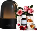 Zwarte aroma diffuser met donker getinte kap, met daaromheen roze rozen, rode rozen, ambergroene kristallen op marmeren blokken en een flesje "AROMA DIFFUSING Floral Dream".