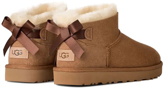 Twee bruine UGG Ultra Mini Bailey Bow laarzen met bruine strikken en UGG logo labels.