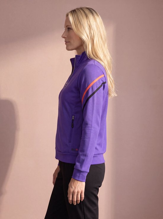 Vrouw van opzij in paars sportvest met ritssluiting, oranje en zwarte strepen op mouw.