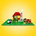 LEGO boerderij met rode huis, schoorsteen, schaap en bruine koe op groene bouwplaat.