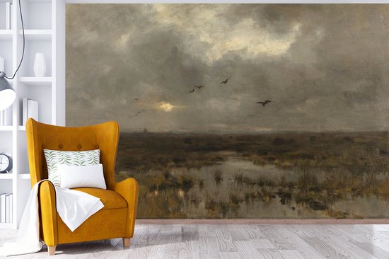 Un fauteuil jaune avec un coussin, face à un tableau de marais avec un ciel sombre et nuageux.