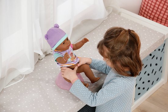 Meisje houdt babypop boven een roze pot. Pop draagt paarse muts en een paars-roze rompertje.