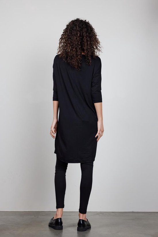 Zicht op de achterkant van een vrouw in zwart Didi jurkje en zwarte legging.