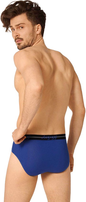Man met getailleerde buik en baard, draagt een blauwe Sloggi slip, van achteren gezien, met zwarte tailleband.