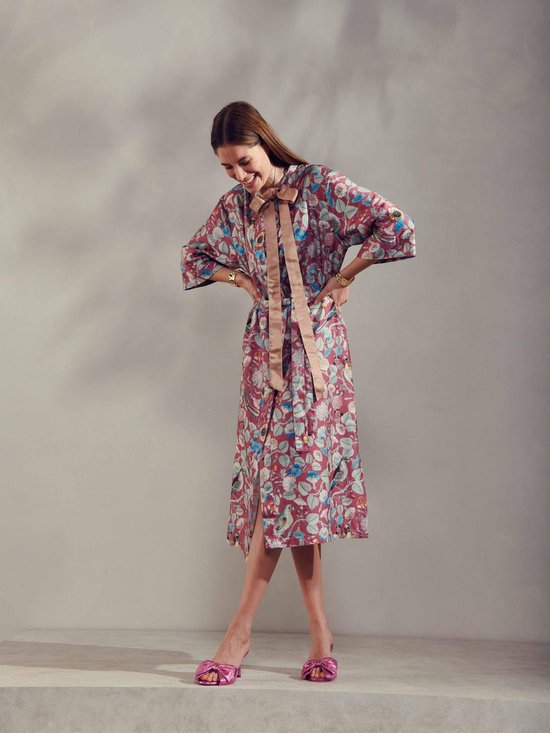 Vrouw met strik in de nek, paarse kimono met bloemen- en vogelprint, ceintuur in de taille.