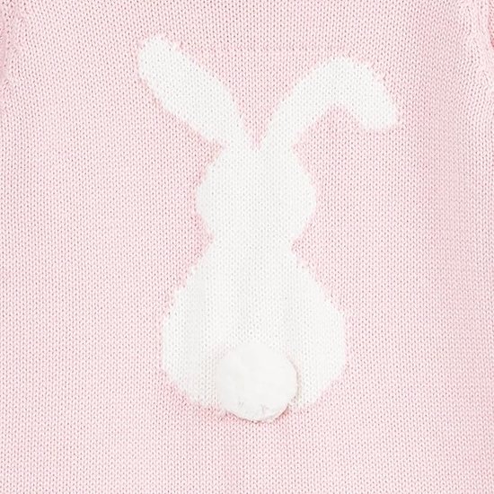 Detailopname van een gebreide roze romper met een witte konijnenprint en een wit pompon-staartje.